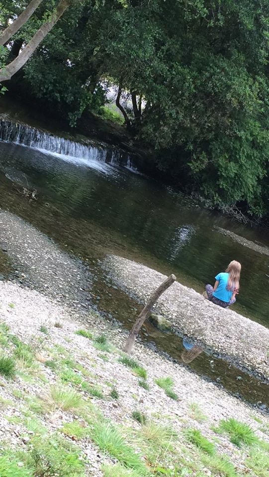 child sitting next to riverbank in Kilbrittain
