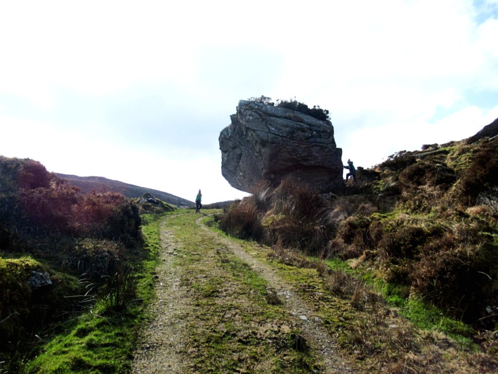 children exploring a large rock beside the mountain path
